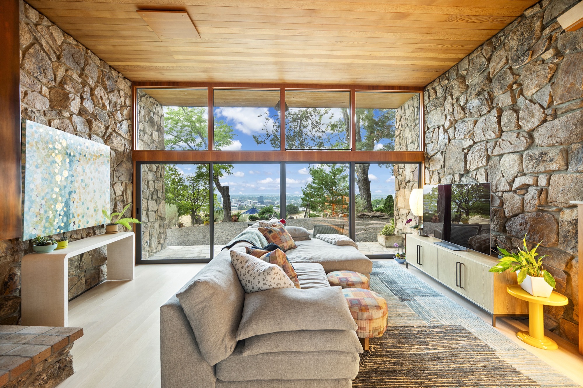 Great room with soaring wood ceilings, stone walls, and walls of glass
